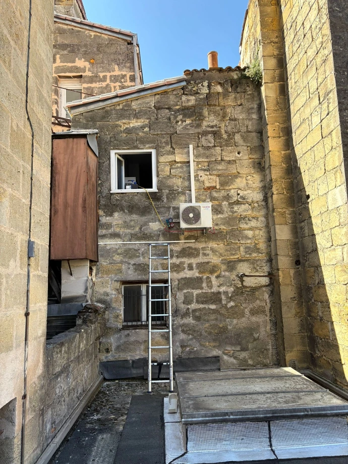 pose d'une clim mono split a l'extérieur sur une cour